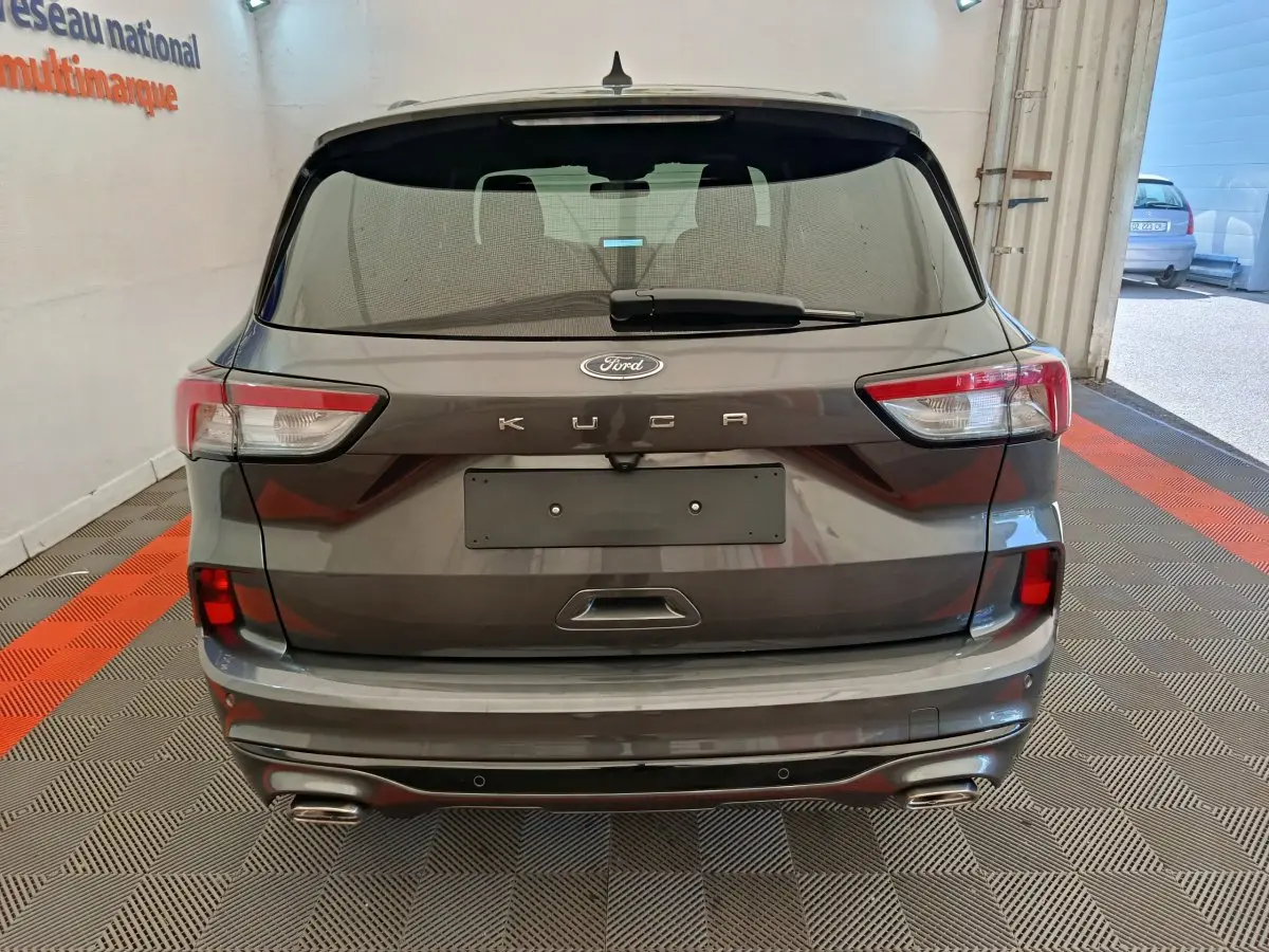 Vue arrière d'un Ford Kuga gris clair 2024 avec feux LED et double sortie d'échappement intégrée au pare-chocs.