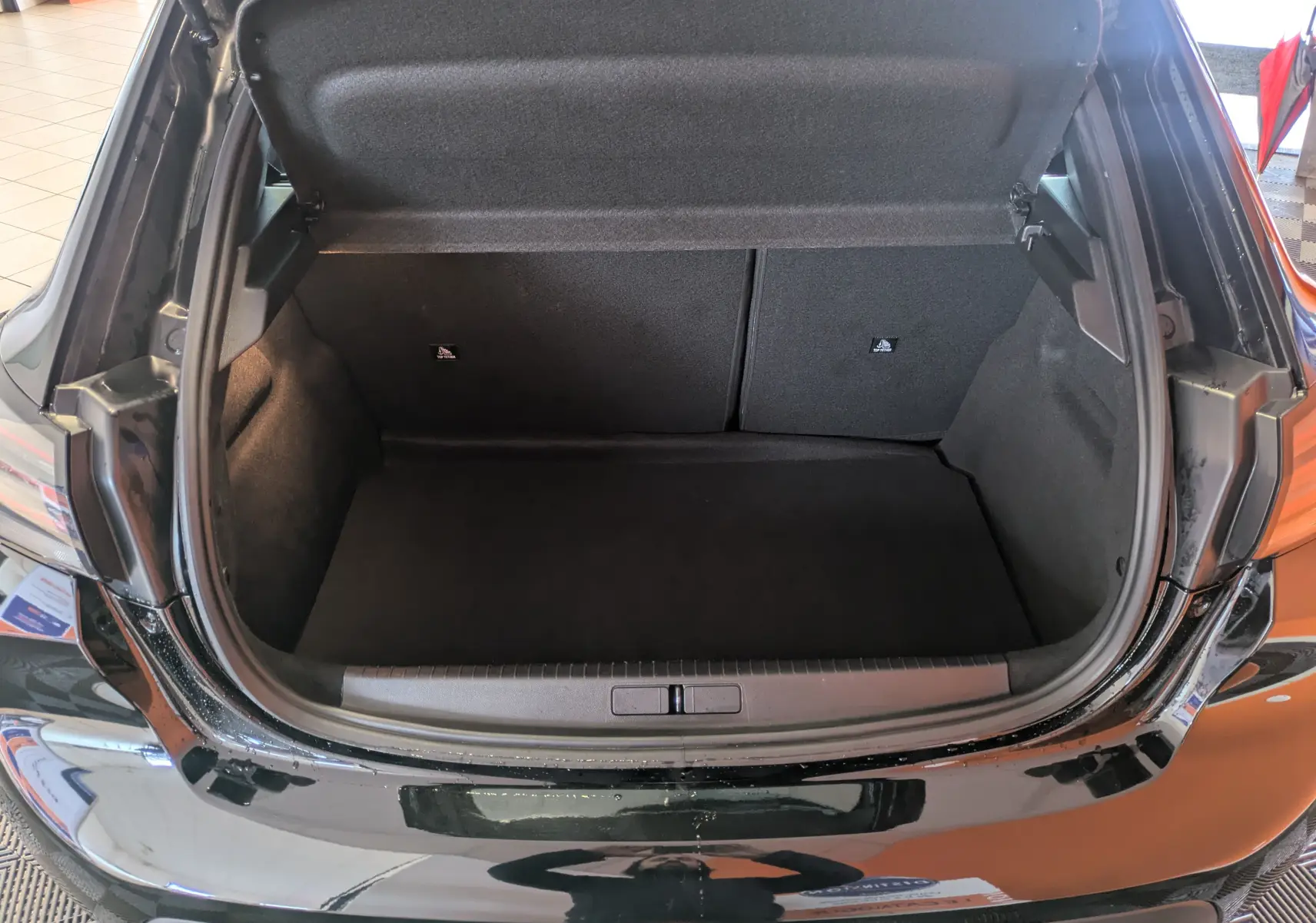 Coffre ouvert vu de l'arrière d'une Peugeot 208 2024 noir perla, montrant l'espace de chargement vide.