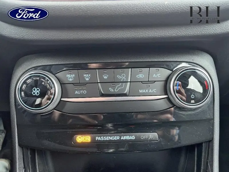 Gros plan sur la console centrale du Ford Puma 2023 gris Solar, montrant les commandes de climatisation et l'indicateur airbag passager.