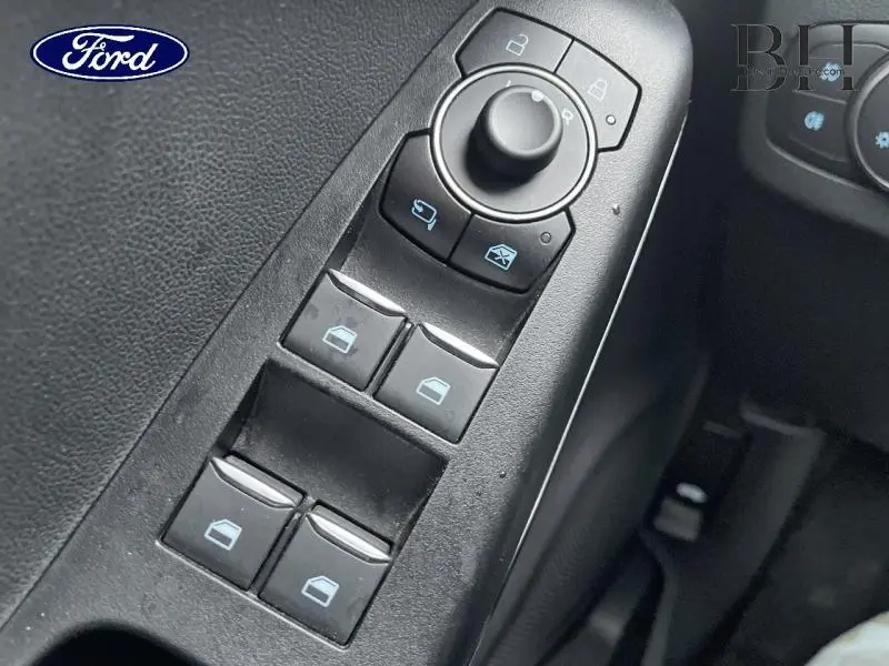 Gros plan sur les commandes de lève-vitres et rétroviseurs côté conducteur du Ford Puma 2023 gris Solar Métallisée.