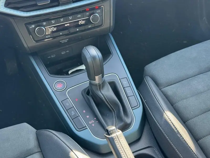 Vue rapprochée de la console centrale noire du SEAT Arona 2025, mettant en valeur le levier de vitesse automatique et la climatisation.