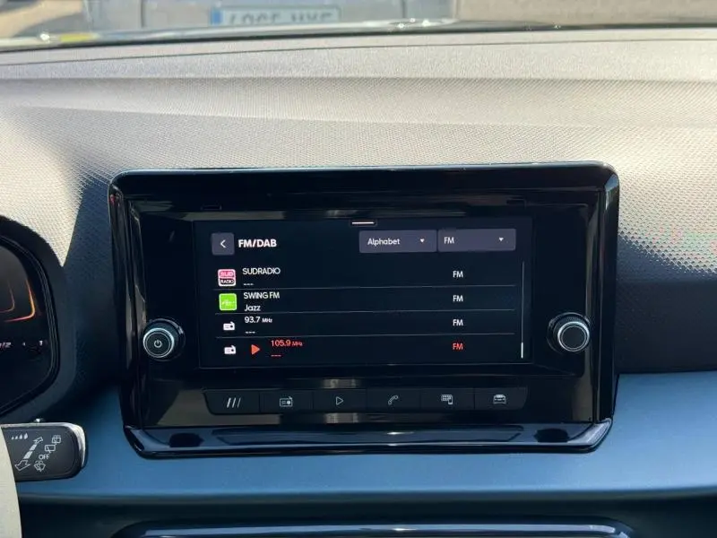 Vue rapprochée de l'écran tactile central noir du tableau de bord du SEAT Arona 2025, affichant les stations radio FM/DAB.