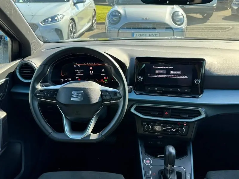 Vue intérieure avant du tableau de bord et volant cuir multifonction d'une SEAT Arona noir avec écran tactile et commandes digitales.