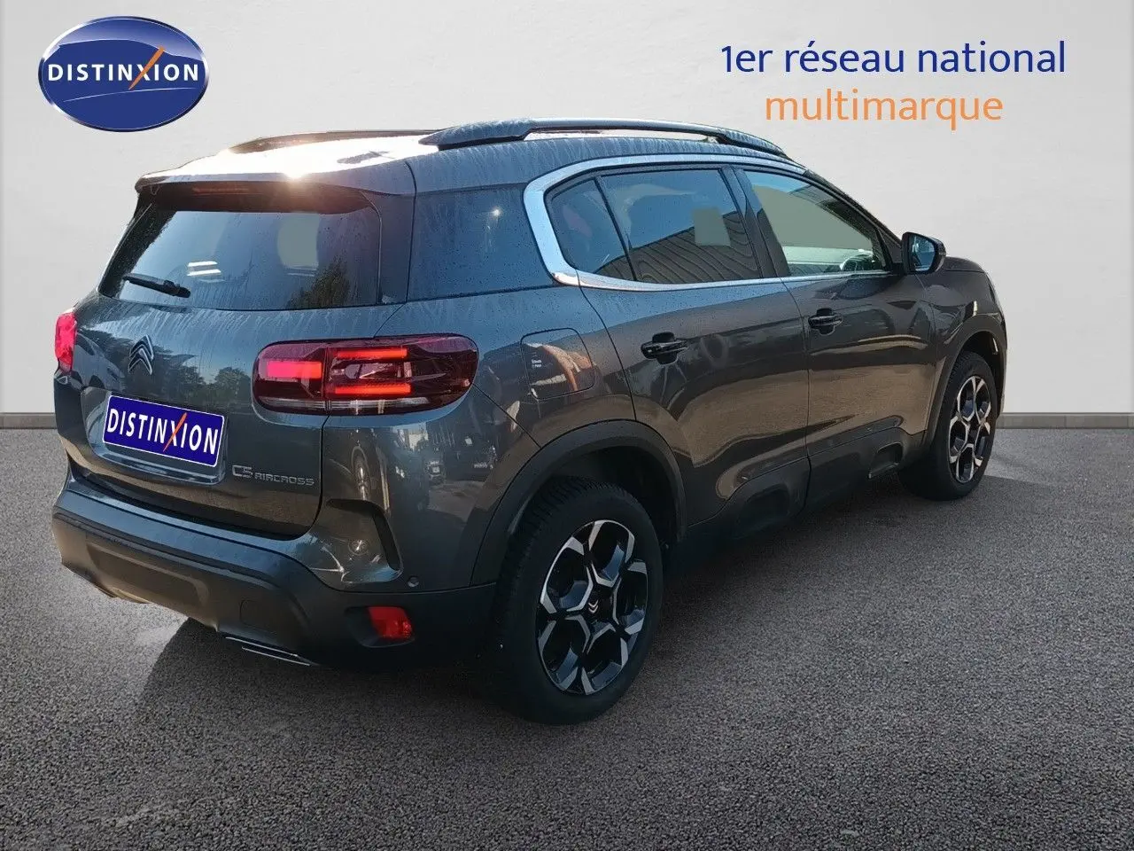 Vue 3/4 arrière droite du Citroën C5 Aircross gris platinium métal avec jantes bi-ton et feux LED allumés.
