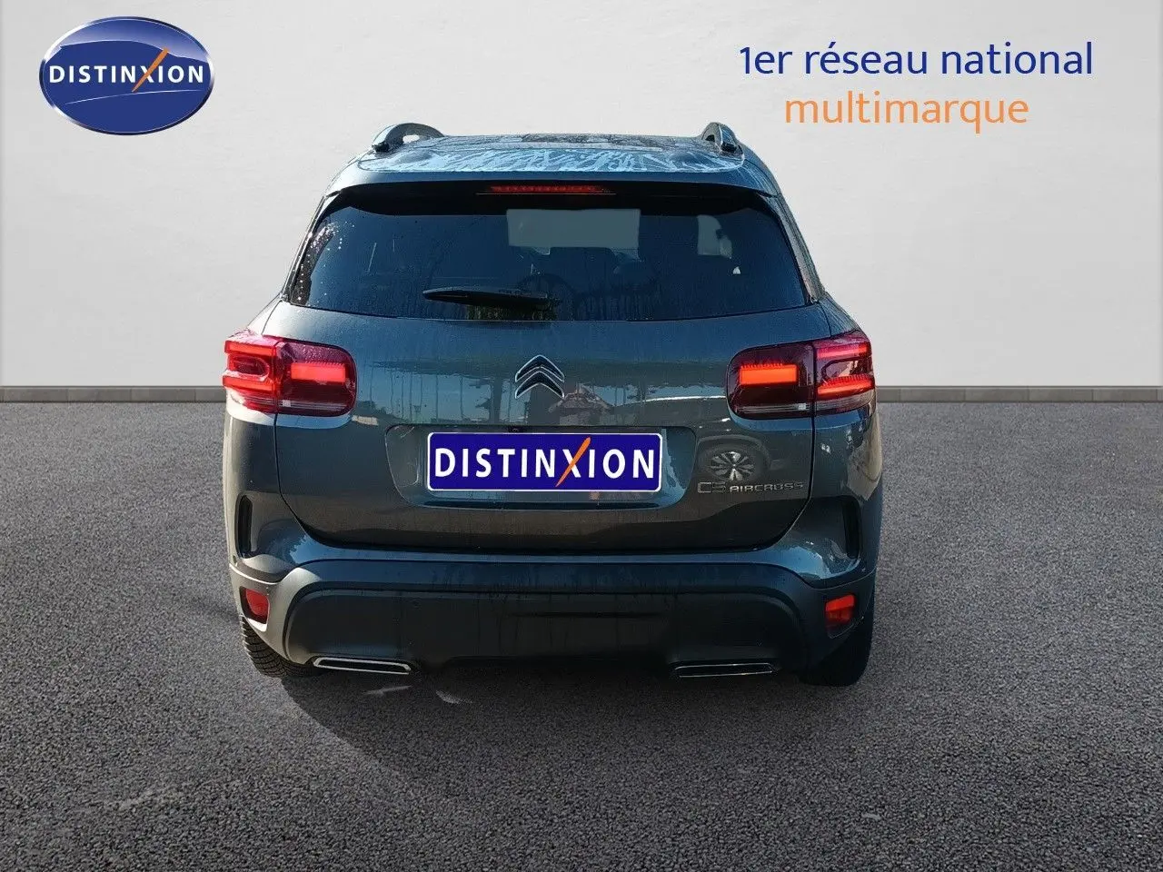 Vue arrière d'un Citroën C5 Aircross gris platinium métal avec feux allumés sur fond neutre.