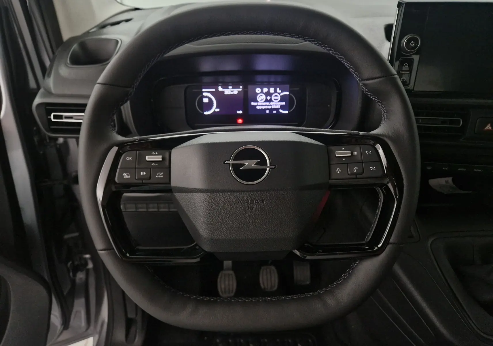 Vue frontale du volant en cuir noir de l'Opel Combo Life gris Artense avec commandes intégrées et tableau de bord numérique.
