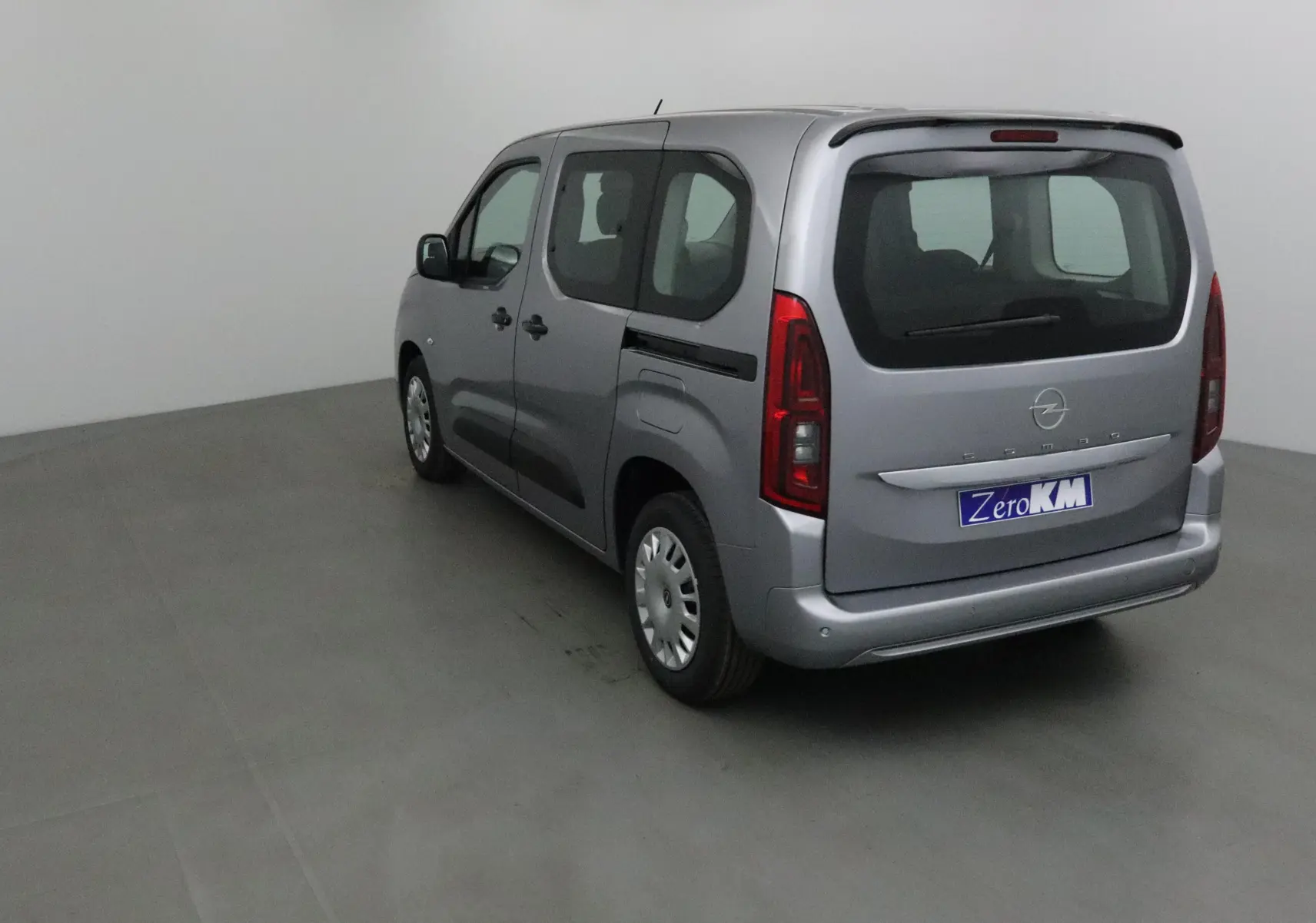 Vue 3/4 arrière droite d'un Opel Combo Life gris Artense avec becquet et vitres teintées en intérieur neutre.