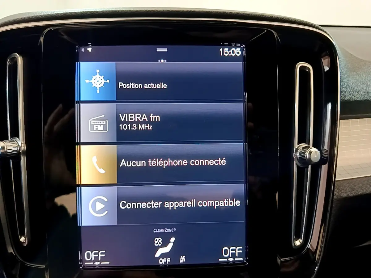 Écran tactile central affichant la radio et la connexion téléphone dans le tableau de bord noir du Volvo XC40 gris clair.