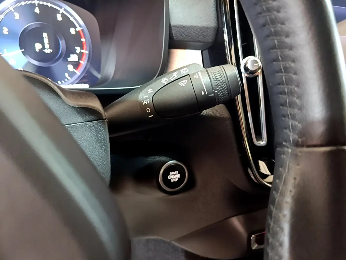 Gros plan sur la manette d'essuie-glace et le bouton démarrage du tableau de bord d'un Volvo XC40 gris clair.