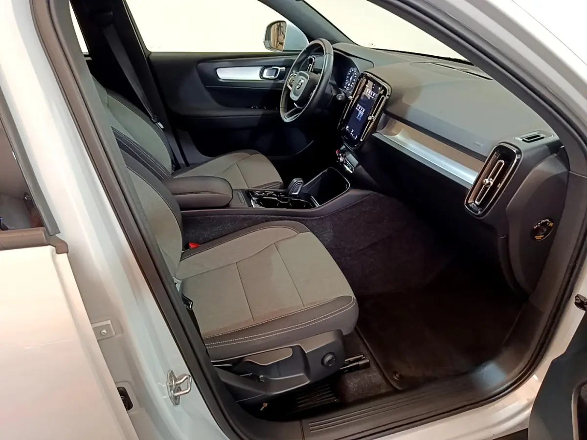 Intérieur côté conducteur du Volvo XC40 gris clair 2020, avec tableau de bord moderne et sièges tissu gris.
