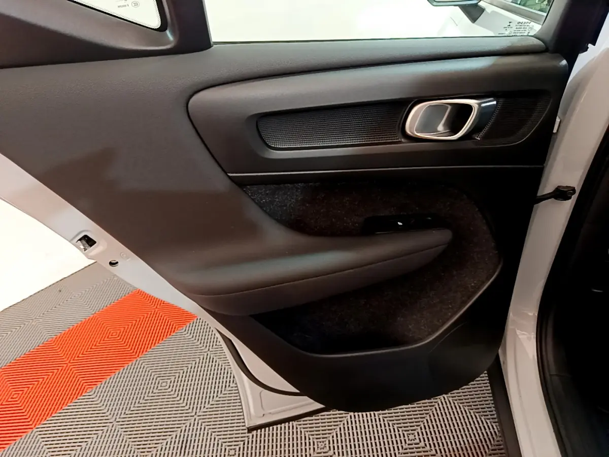 Porte arrière droite ouverte du Volvo XC40 gris clair, montrant le panneau intérieur noir avec poignée chromée.