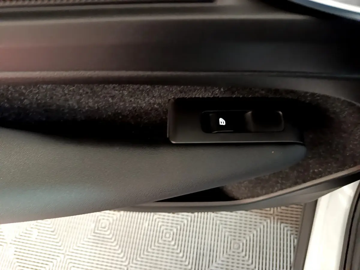 Gros plan sur le bouton de verrouillage des portes dans la portière intérieure noire du Volvo XC40 T2 2020 gris clair.