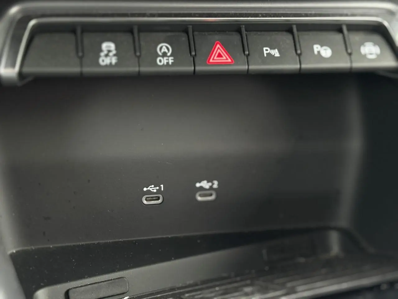Gros plan sur la console centrale noire de l'Audi A3 Berline 2024 avec deux ports USB-C et boutons de commande au-dessus.
