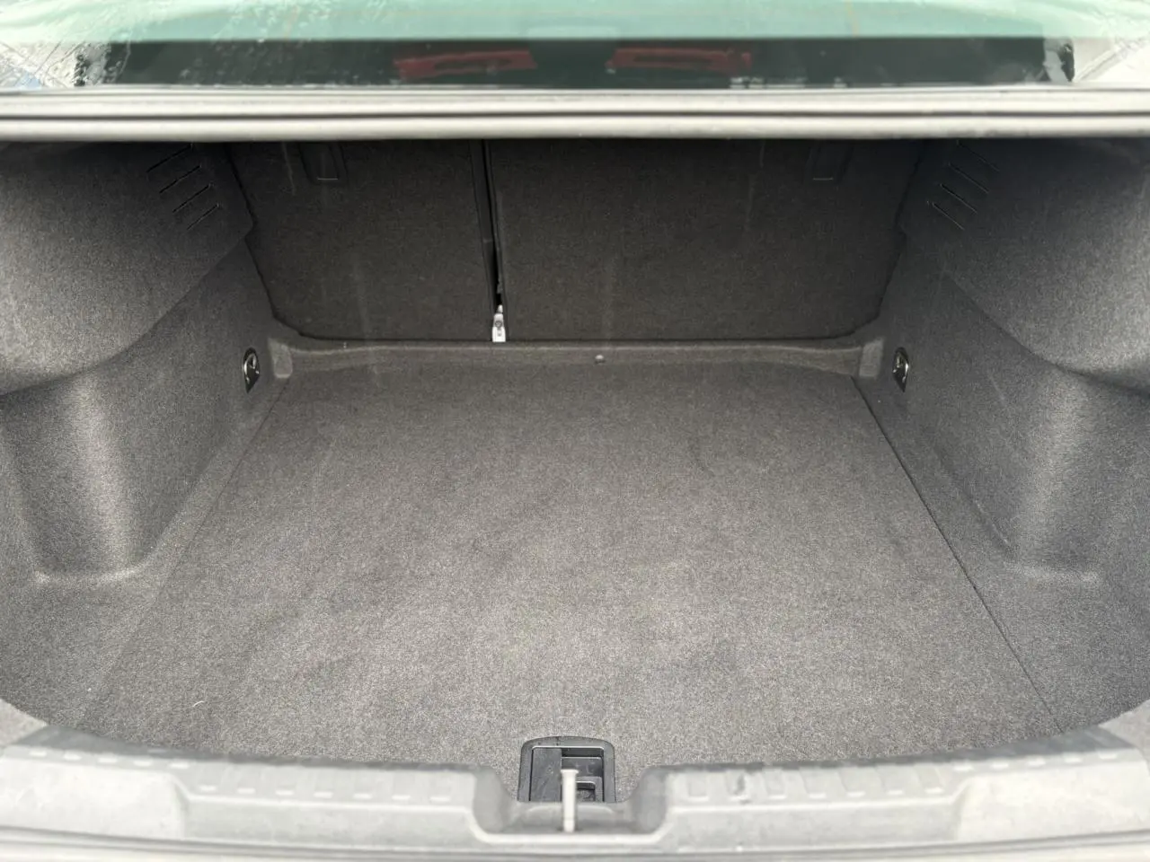 Coffre vide de l'Audi A3 Berline 2024 en vue intérieure, montrant le revêtement gris et l'espace de chargement.