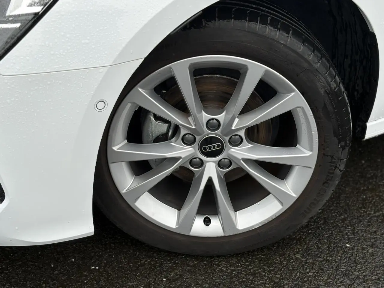 Gros plan sur la jante alliage 17 pouces argentée de l'Audi A3 Berline blanc Arkona, côté avant droit.