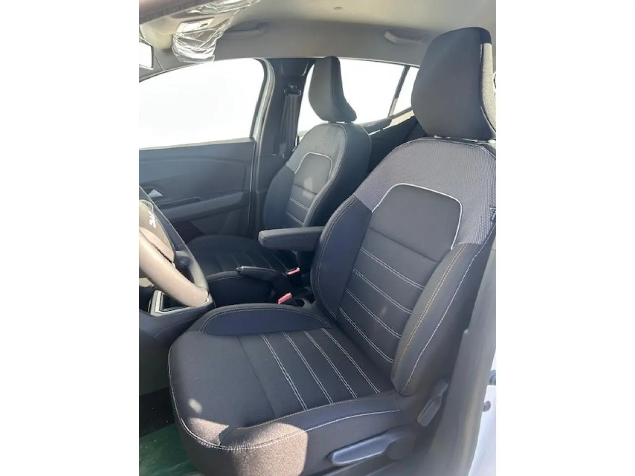 Vue intérieure côté gauche montrant les sièges avant noirs avec sellerie spécifique Stepway de la Dacia Sandero III blanche.