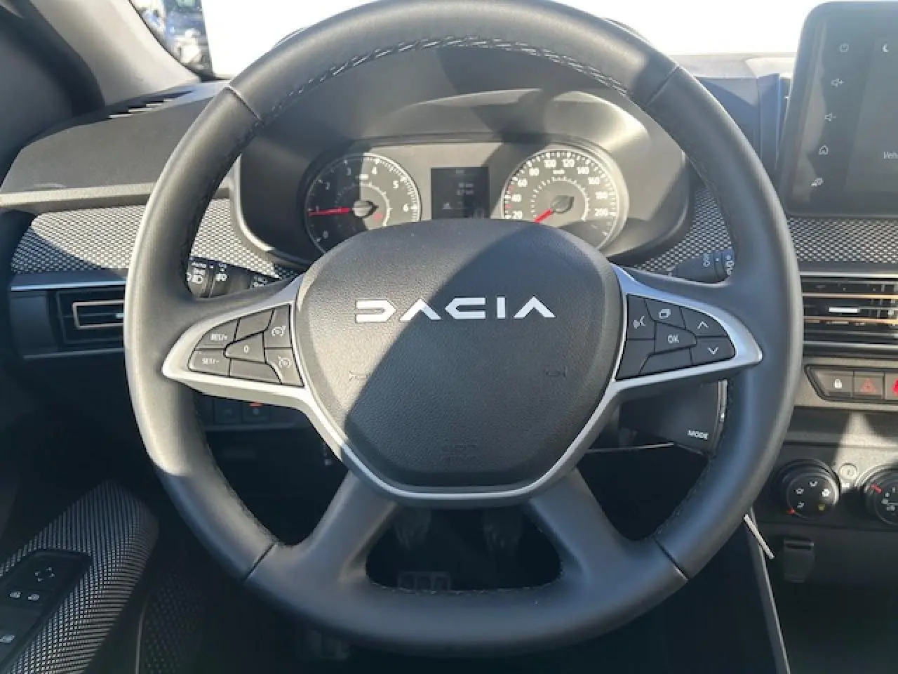 Vue rapprochée du volant noir de la Dacia Sandero Stepway 2025 avec commandes intégrées et tableau de bord numérique.