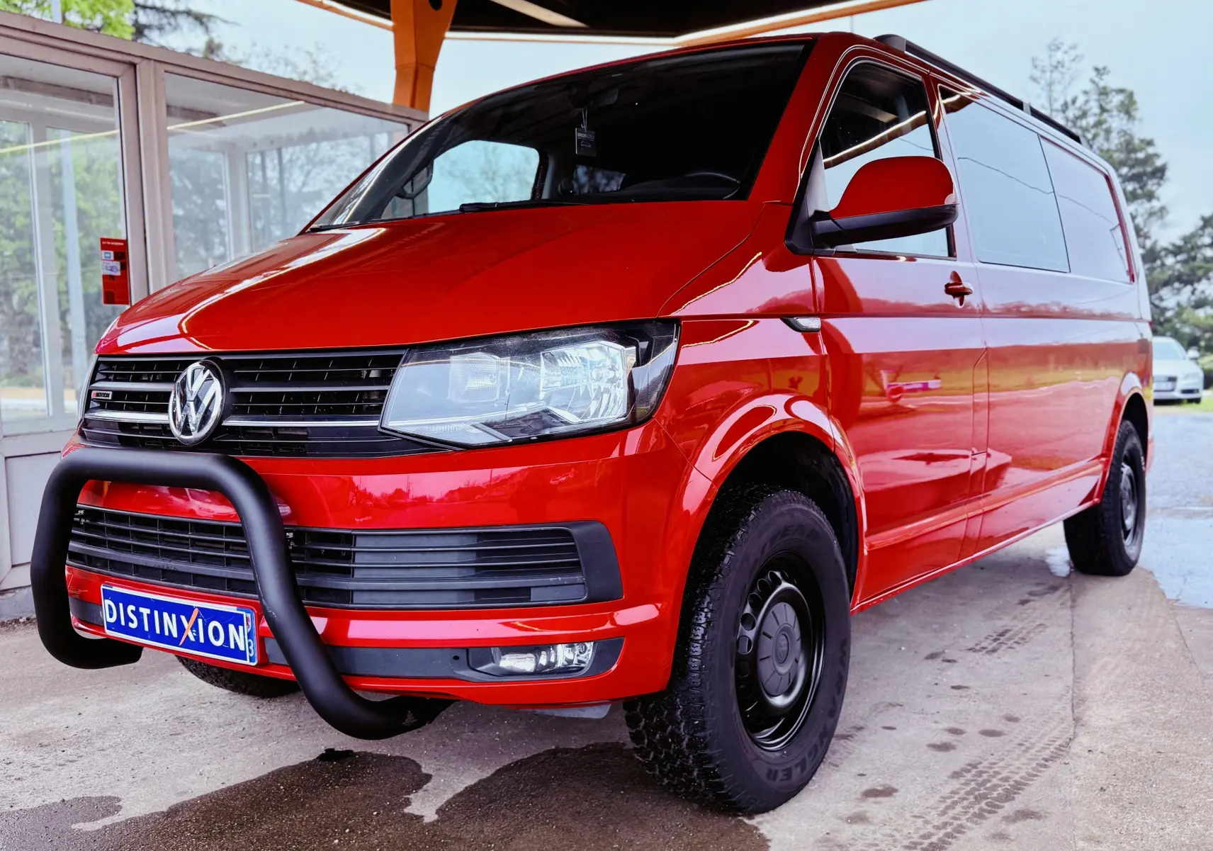 Vue 3/4 avant droit d’un Volkswagen Transporter double cabine rouge 2017 avec pare-buffle noir et jantes acier noires.