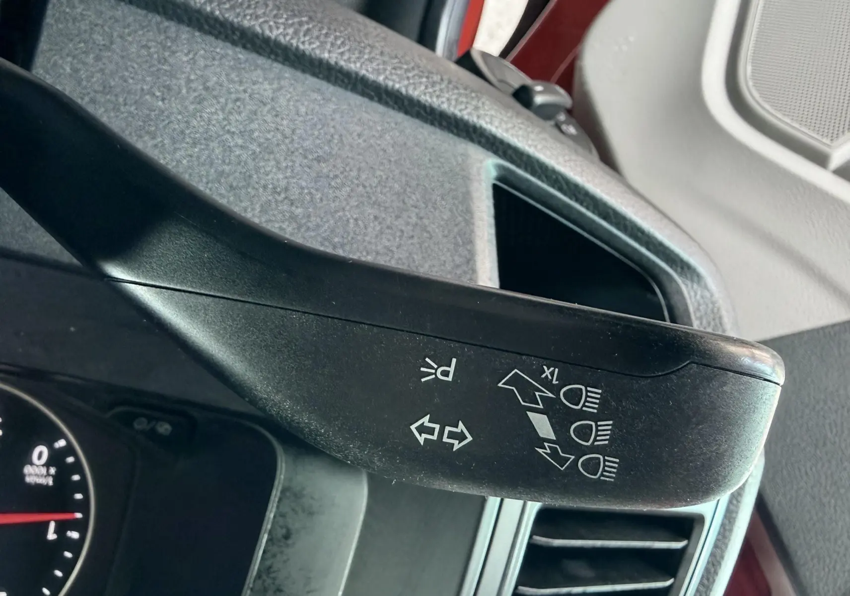 Gros plan sur la manette de clignotants noire à l'intérieur d'un Volkswagen Transporter rouge, côté conducteur.