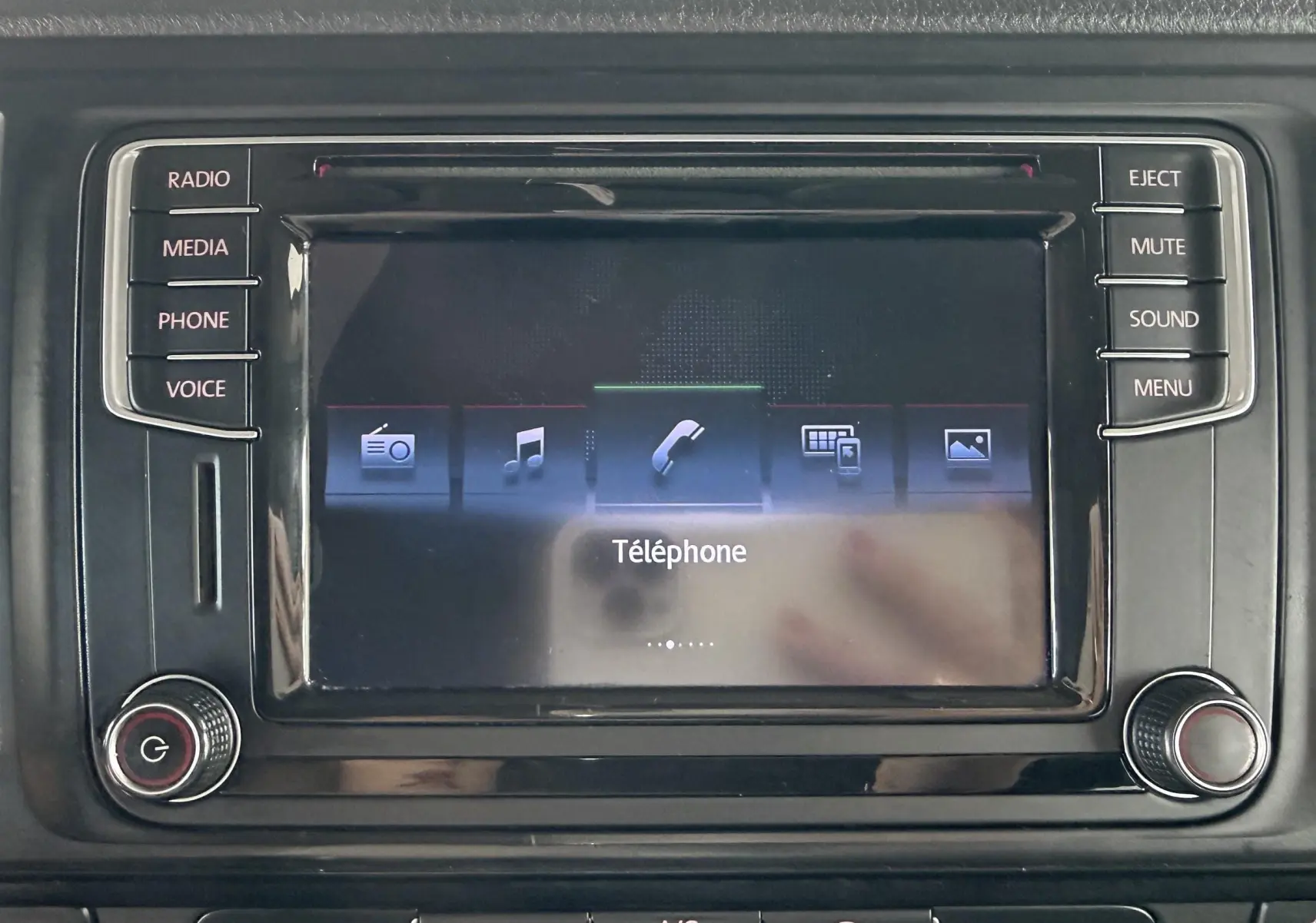Écran tactile central du Volkswagen Transporter rouge, affichant le menu téléphone avec boutons physiques autour.