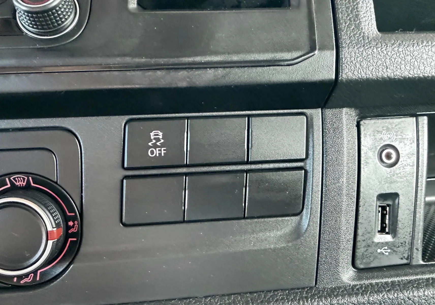 Détail du tableau de bord noir du Volkswagen Transporter rouge, avec bouton de contrôle de stabilité et prise USB visible.