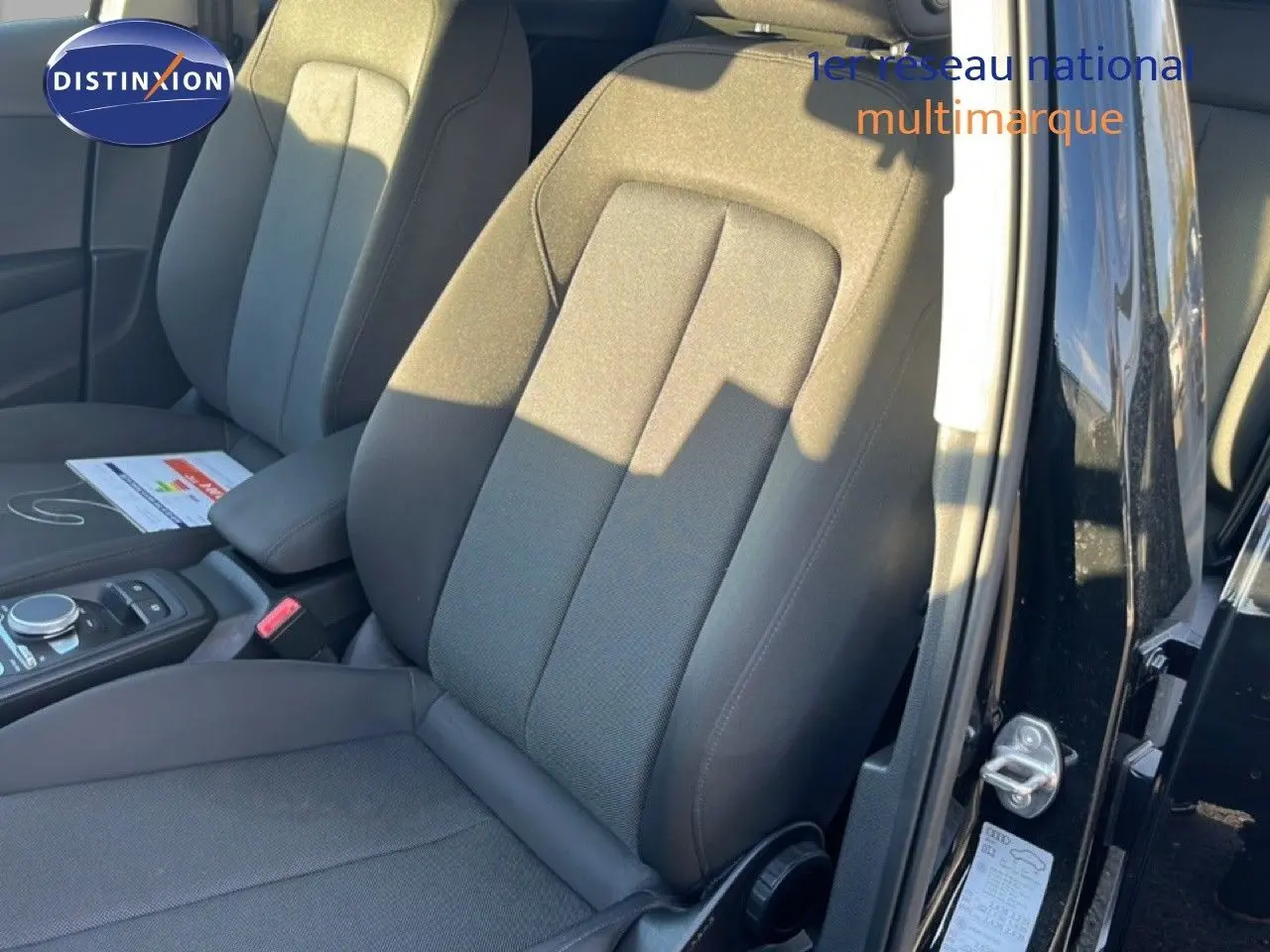 Gros plan sur les sièges avant en tissu noir du côté gauche d'un Audi Q2 noir mito metal 2023 avec porte ouverte.