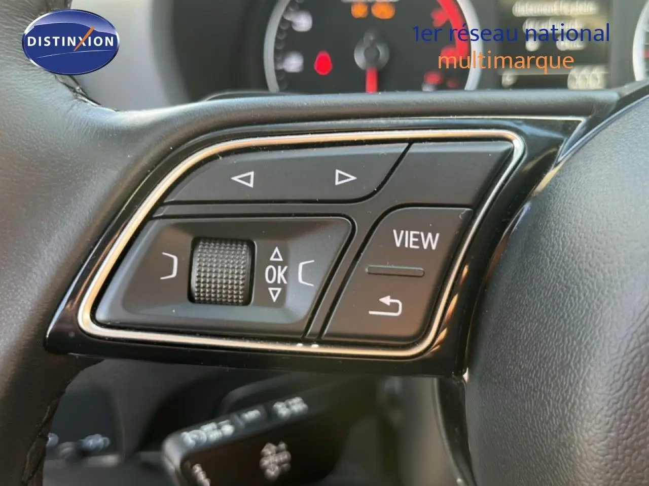 Gros plan sur les commandes au volant de l'Audi Q2 35 TFSI S-Line, avec boutons multifonctions et molette tactile.