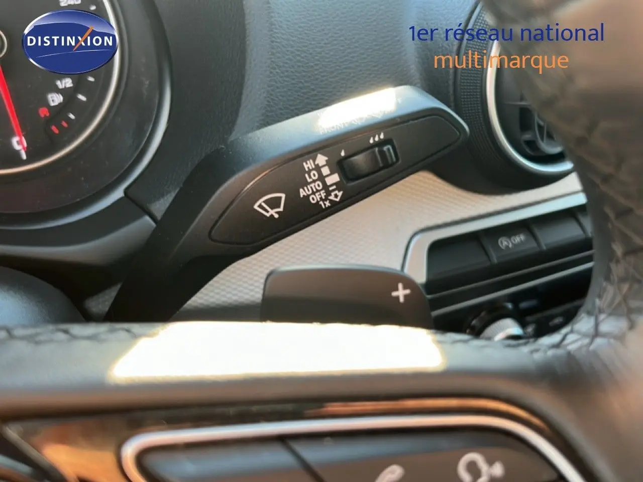 Gros plan sur la commande d'essuie-glace et palette de changement de vitesse derrière le volant d'un Audi Q2 noir Mito Metal.