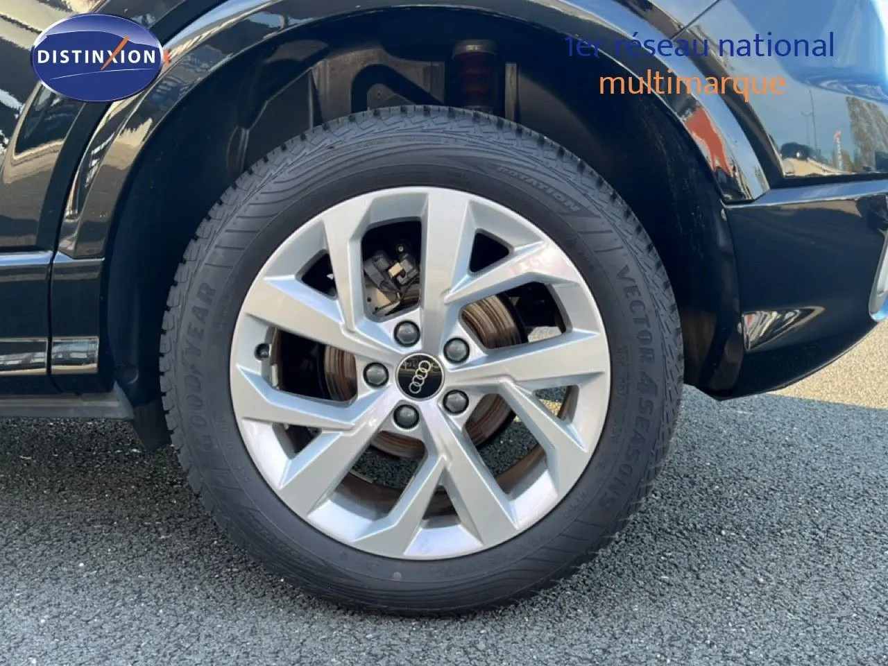 Gros plan sur la roue avant droite d'un Audi Q2 noir mito metal avec jante argentée à plusieurs branches.