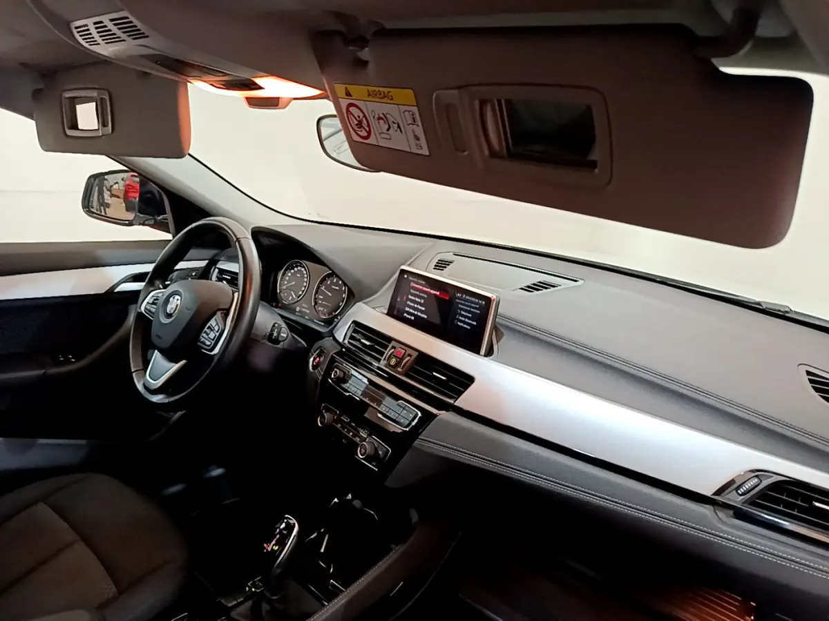 Vue intérieure côté conducteur du tableau de bord et volant cuir noir du BMW X2 sDrive18i 2023 avec écran central digital.