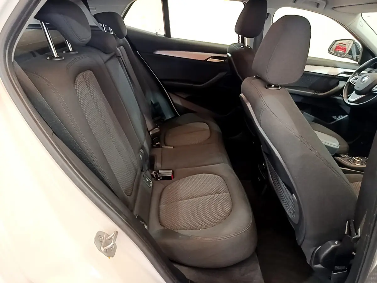 Vue intérieure côté gauche montrant les sièges arrière noirs et une partie du tableau de bord du BMW X2 blanc 2023.