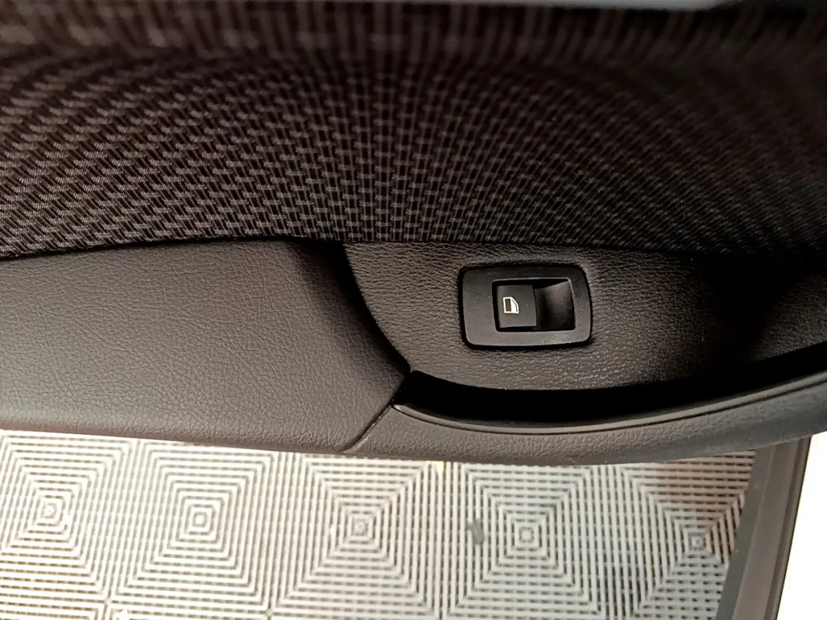 Bouton de verrouillage des portes sur la garniture intérieure noire d'une BMW X2 blanche, vue rapprochée côté porte.