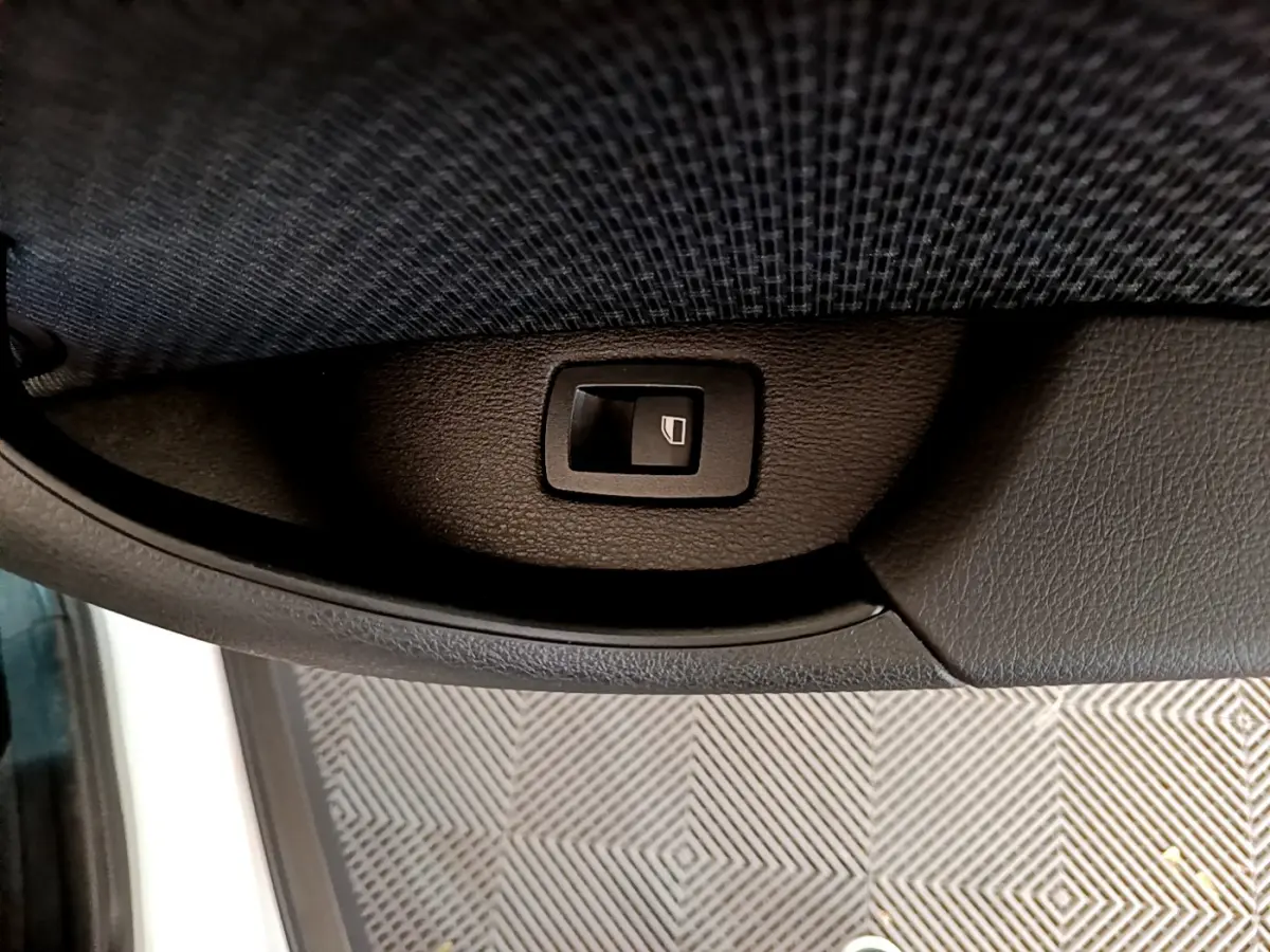 Bouton de commande de lève-vitre sur la portière côté gauche d'un BMW X2 blanc 2023, finition Business Design.