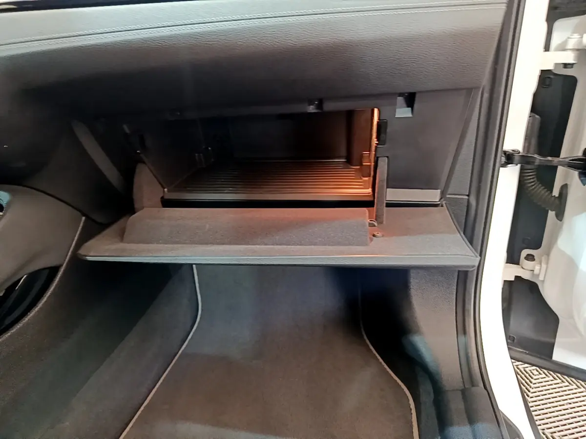 Gros plan sur la boîte à gants ouverte côté passager d'une BMW X2 blanc 2023, intérieur noir.