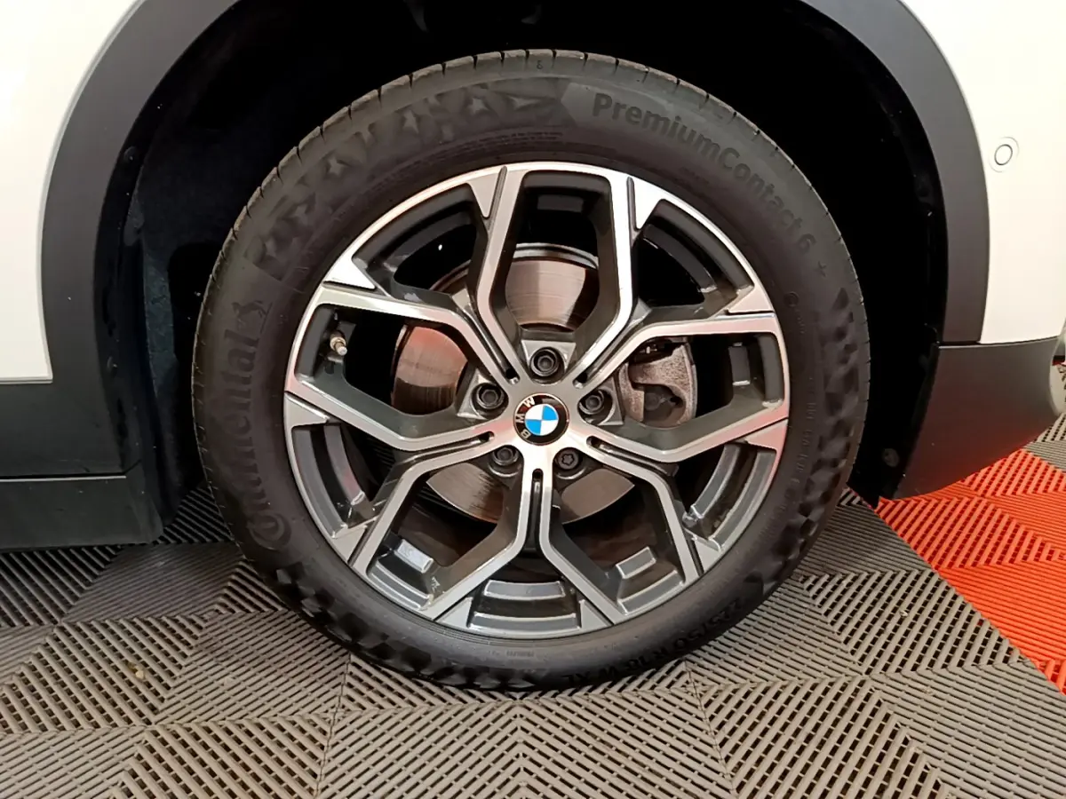 Gros plan sur la roue avant droite avec jante alliage et logo BMW du BMW X2 blanc 2023 sDrive18i Business DesignDKG7.