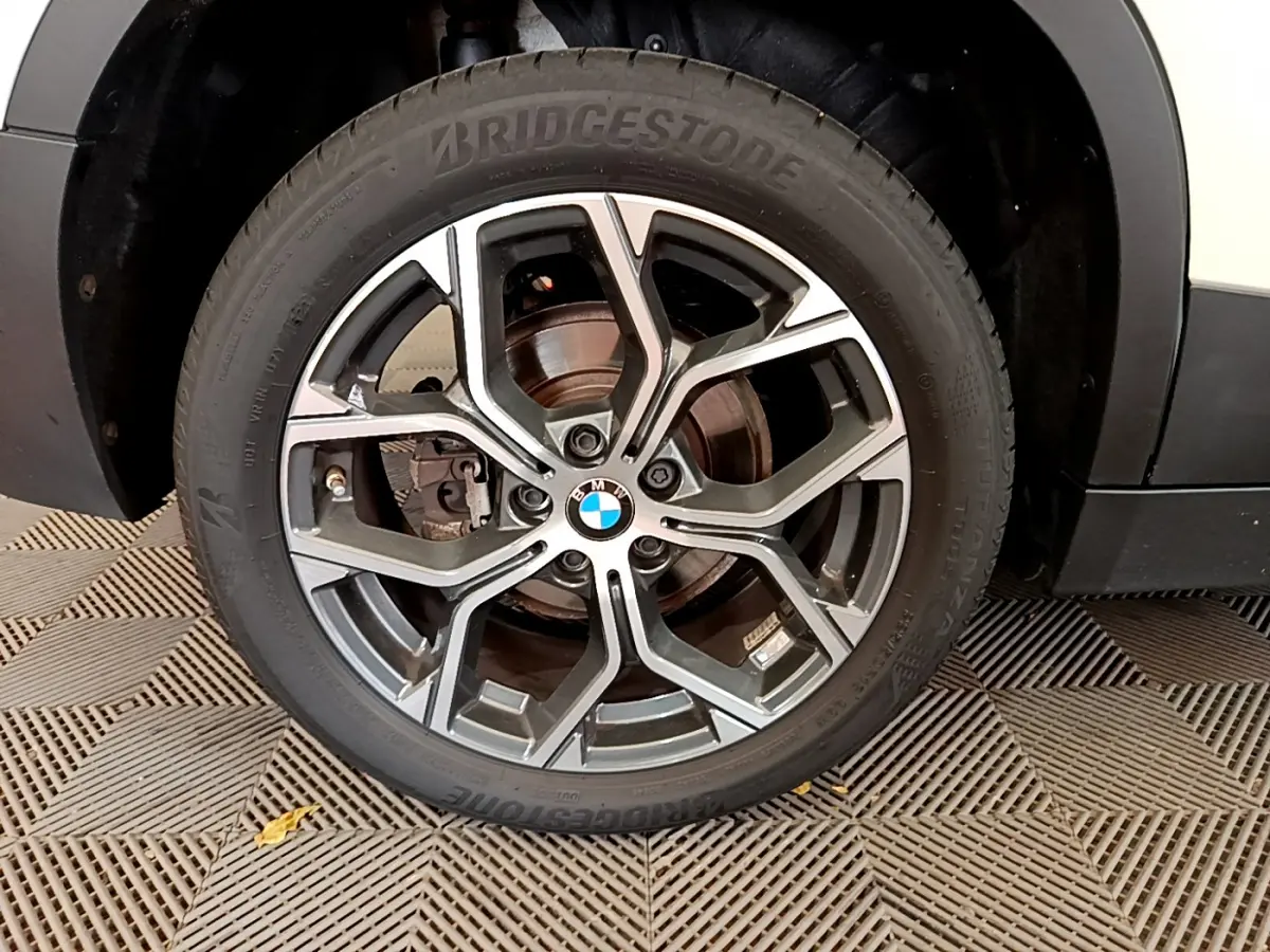 Gros plan sur la roue avant droite d’un BMW X2 blanc 2023 avec jante alliage et pneu Bridgestone visible.