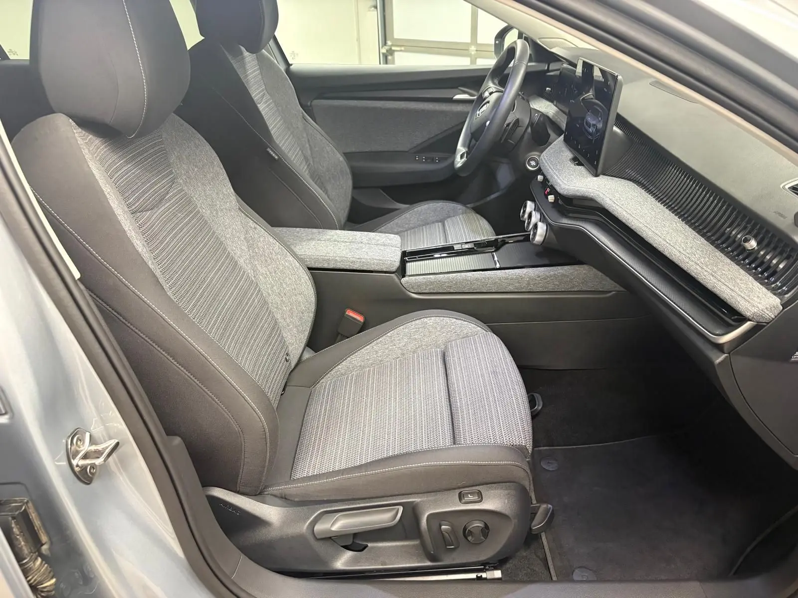 Intérieur de la Skoda Superb Combi 2025 en gris argent, vue côté conducteur montrant sièges et tableau de bord moderne.