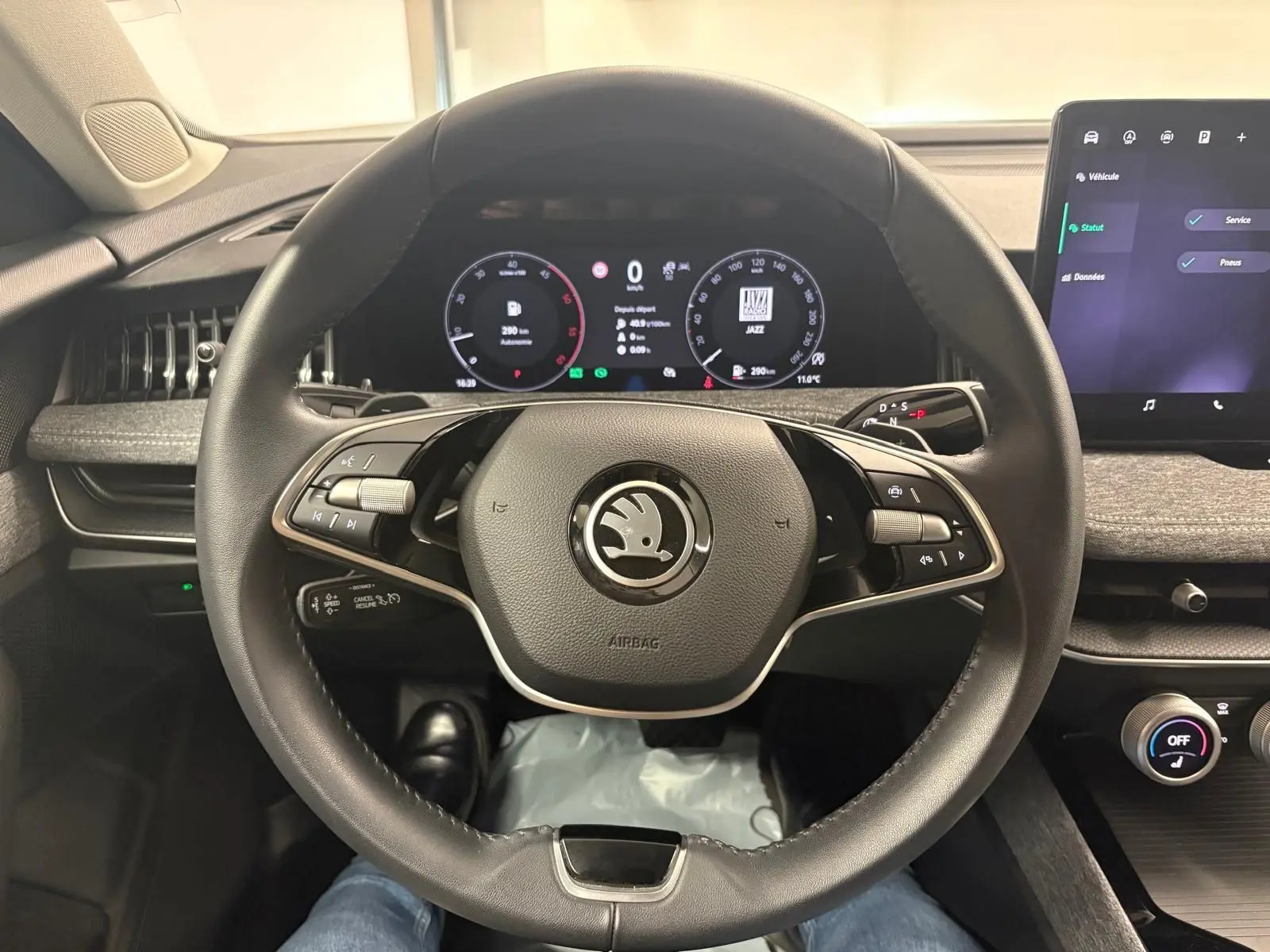 Vue intérieure centrée sur le volant noir de la Skoda Superb Combi 2025 avec tableau de bord numérique et écran tactile.