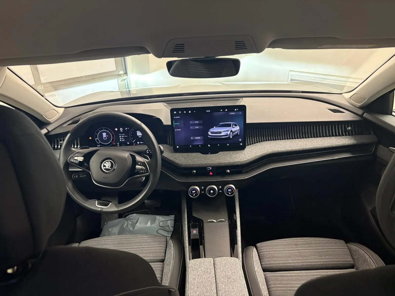 Vue intérieure avant de la Skoda Superb Combi 2025 gris argent, mettant en valeur le tableau de bord moderne et l’écran tactile central.