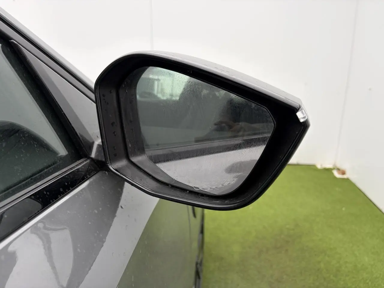 Rétroviseur côté gauche d’une Peugeot 308 gris selenium, avec carrosserie et vitre partiellement visibles.