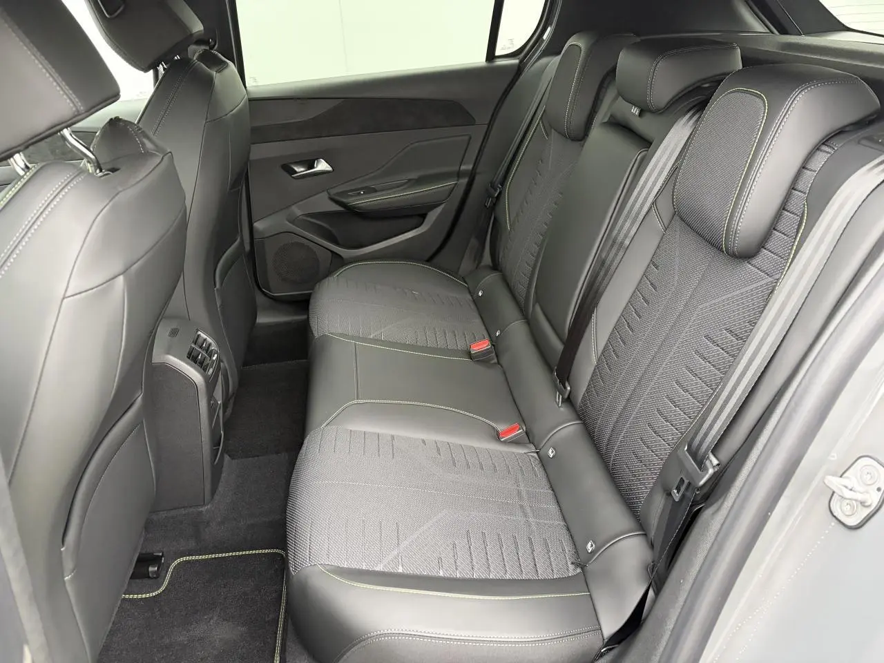 Vue intérieure côté droit des sièges arrière en cuir noir avec surpiqûres vert Adamite de la Peugeot 308 III hybride 2025.