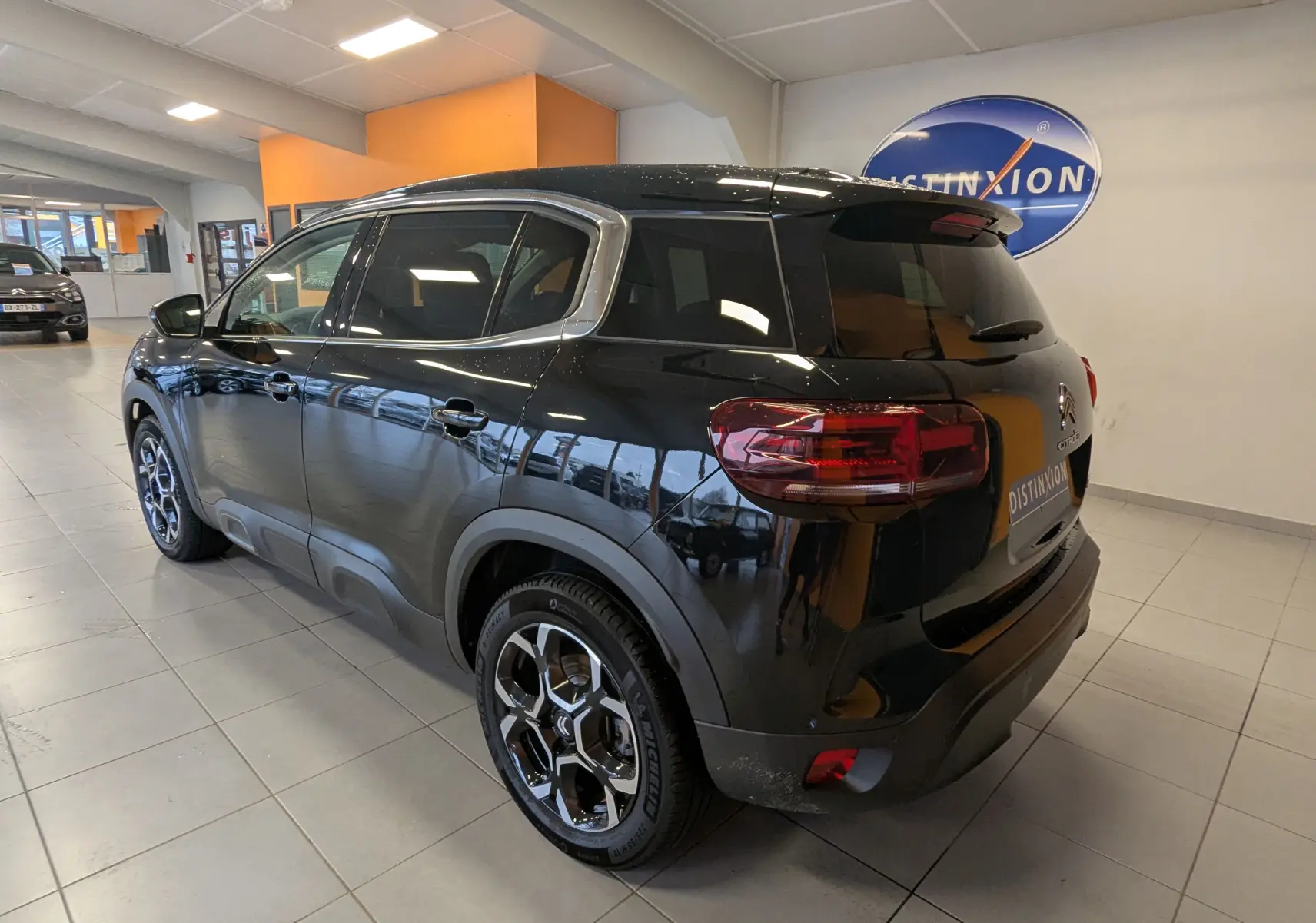 Vue 3/4 arrière droite d'un Citroën C5 Aircross noir 2024 avec jantes alliage 18 pouces en showroom.