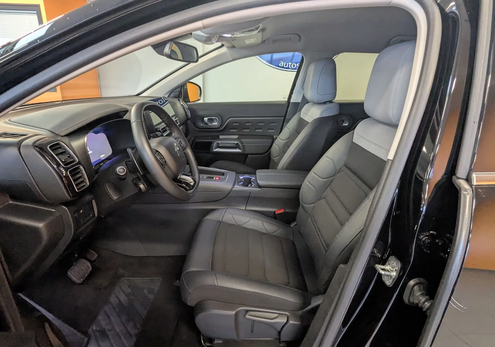Intérieur avant droit du Citroën C5 Aircross noir 2024, sièges tissu gris et volant cuir, tableau de bord moderne visible.