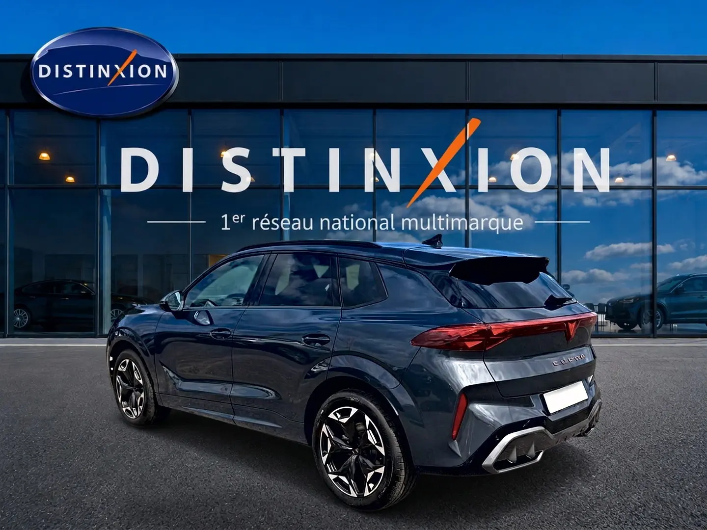 Vue 3/4 arrière droite d'un CUPRA Terramar gris Timanfaya avec jantes 19 pouces et feux arrière LED, devant une vitrine Distinxion.