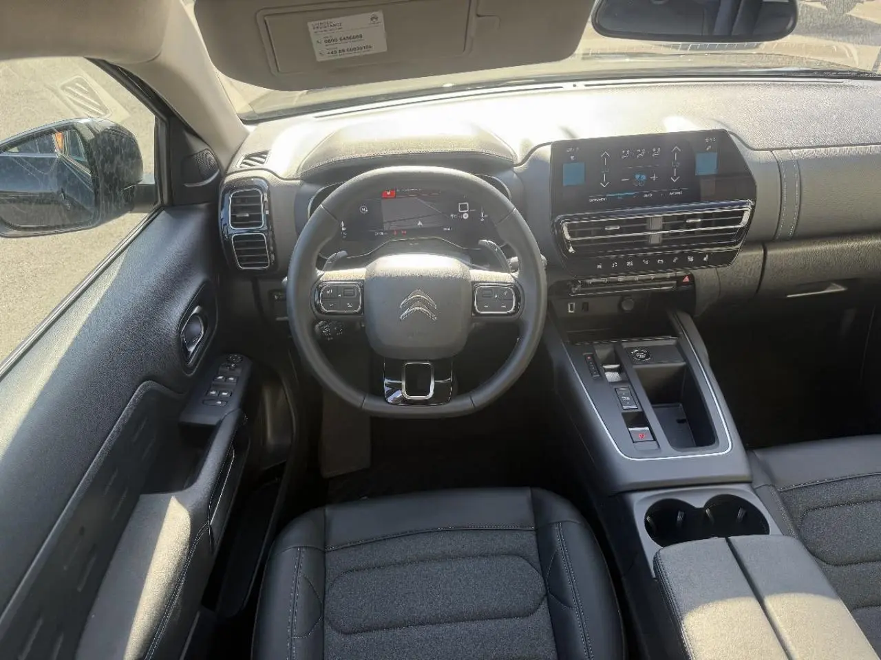 Vue intérieure avant du Citroën C5 Aircross 2025, tableau de bord et volant noirs avec écran tactile central.
