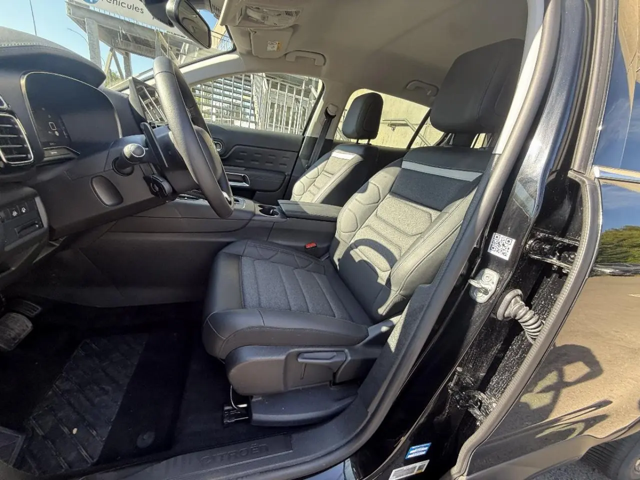 Vue intérieure côté conducteur du Citroën C5 Aircross 2025 avec sièges en tissu et cuir noir, tableau de bord moderne.