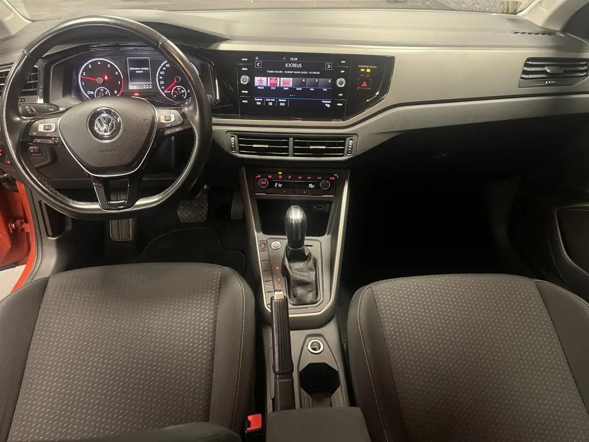 Vue intérieure avant de la Volkswagen Polo Lounge Business 2019, tableau de bord noir avec écran tactile et volant cuir multifonction.