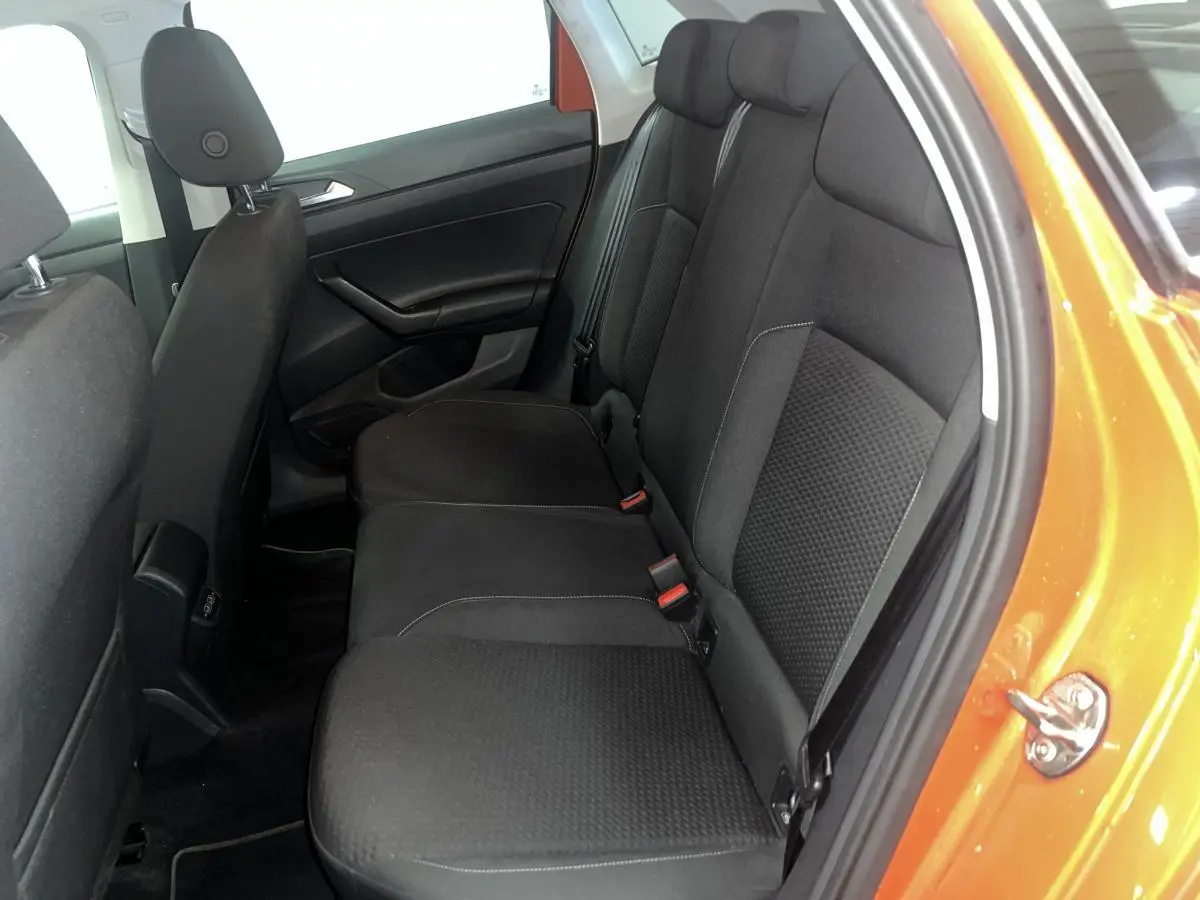Vue côté droit de la banquette arrière noire dans une Volkswagen Polo orange 2019 avec porte ouverte.