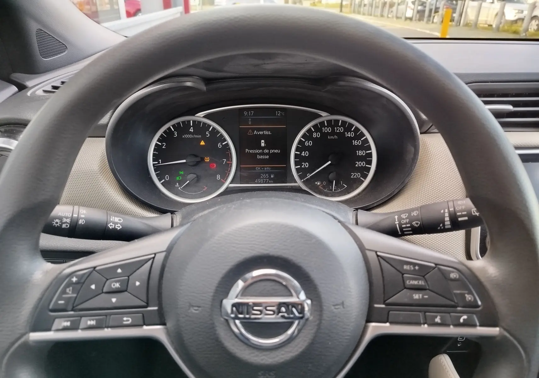 Vue intérieure du volant Nissan Micra blanc 2019, avec tableau de bord digital et commandes au volant visibles.