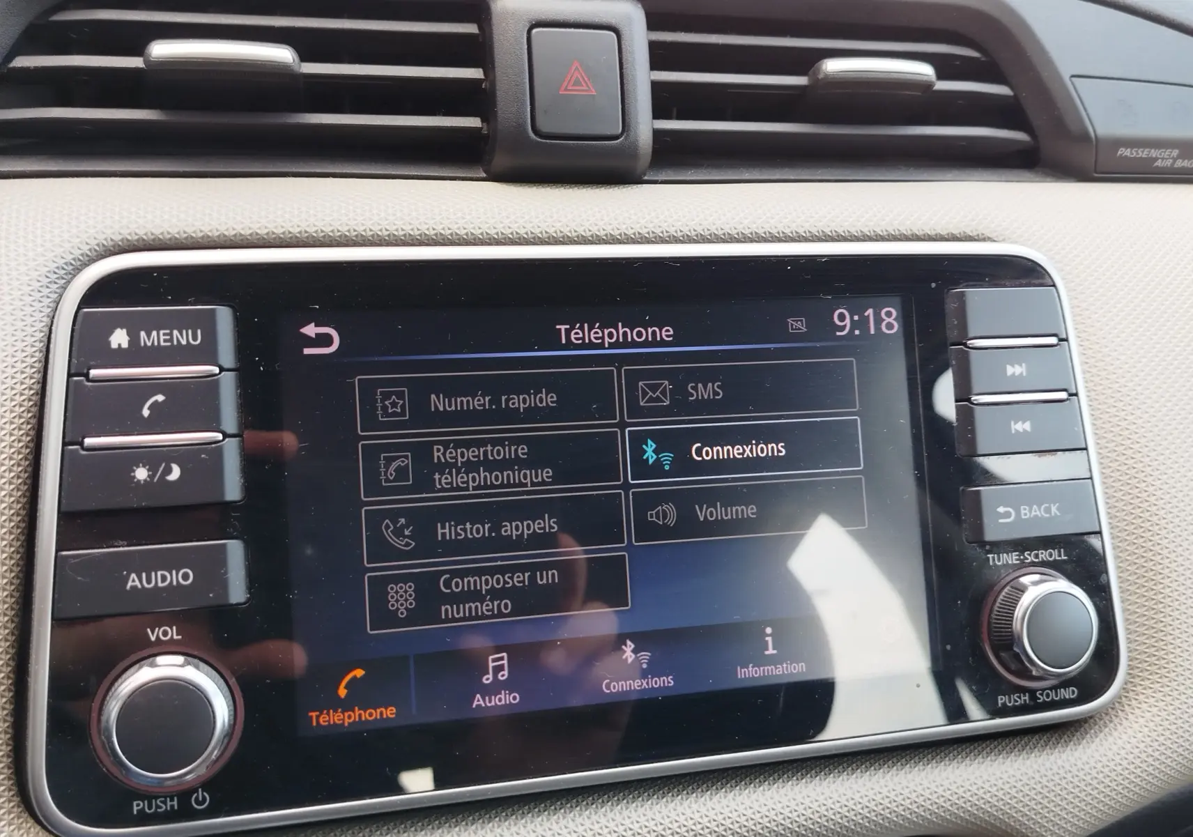 Écran tactile central du tableau de bord de la Nissan Micra blanche, affichant le menu téléphone à 9h18.